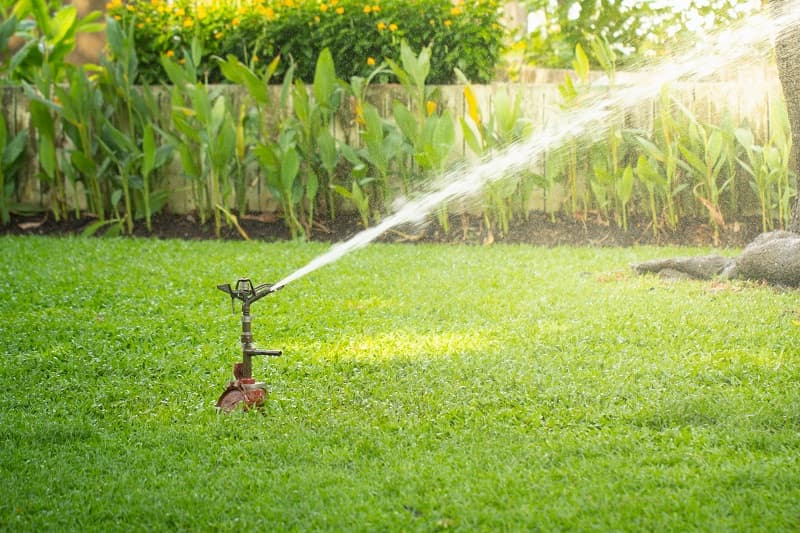 Sprinkler,Watering,Grass,In,Garden,Under,Sunlight,On,Blurred,Background.